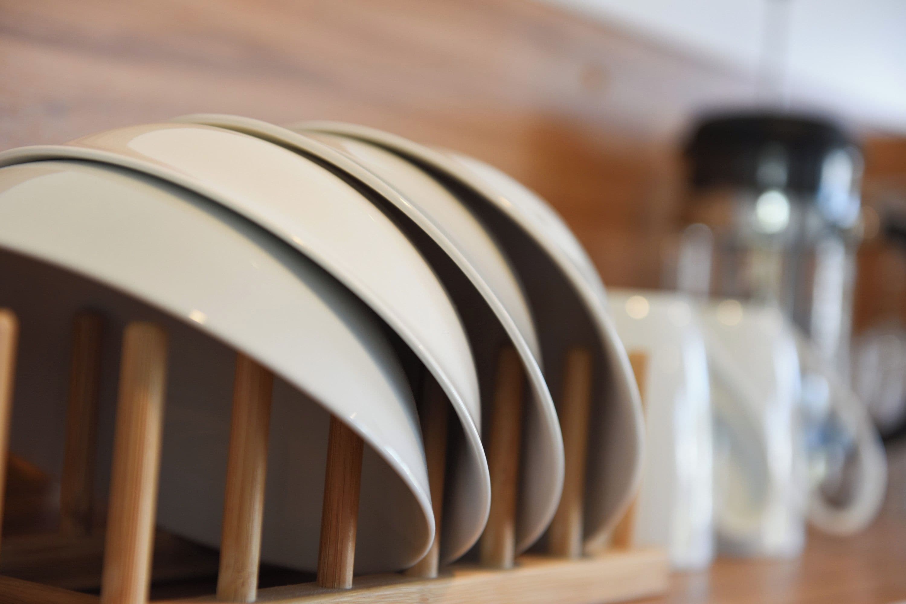 A row of white plates on a wooden rack.