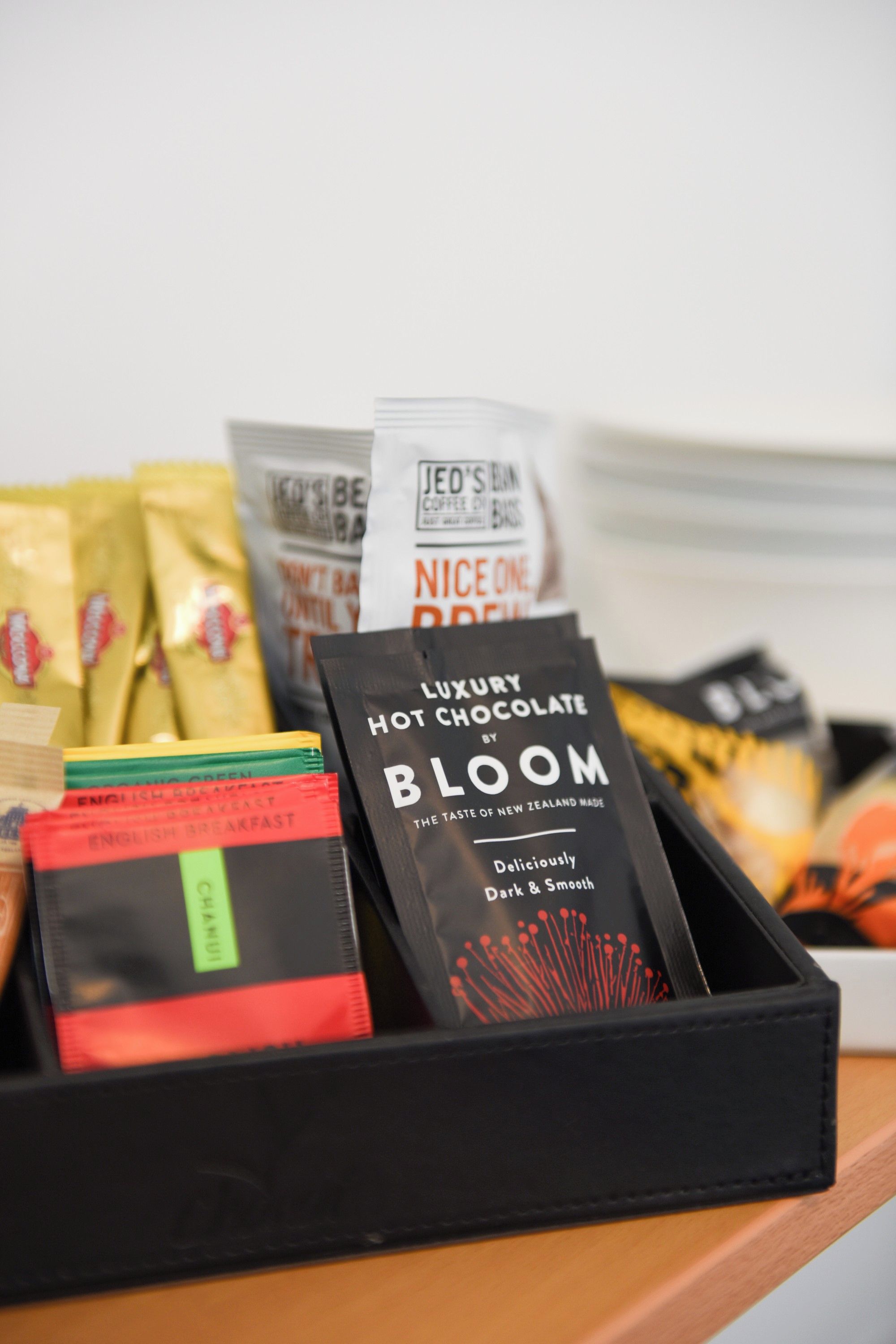 A variety of packaged food items, including a box labeled 'HOT CHOCOLATE BY BLOOM' and other snacks.