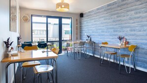 Un espace repas moderne avec une grande fenêtre, des chaises en métal et une table en bois.