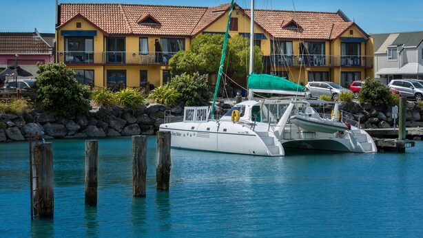Une propriété située au bord de l’eau, avec un bateau amarré devant un bâtiment jaune doté d’un toit rouge.