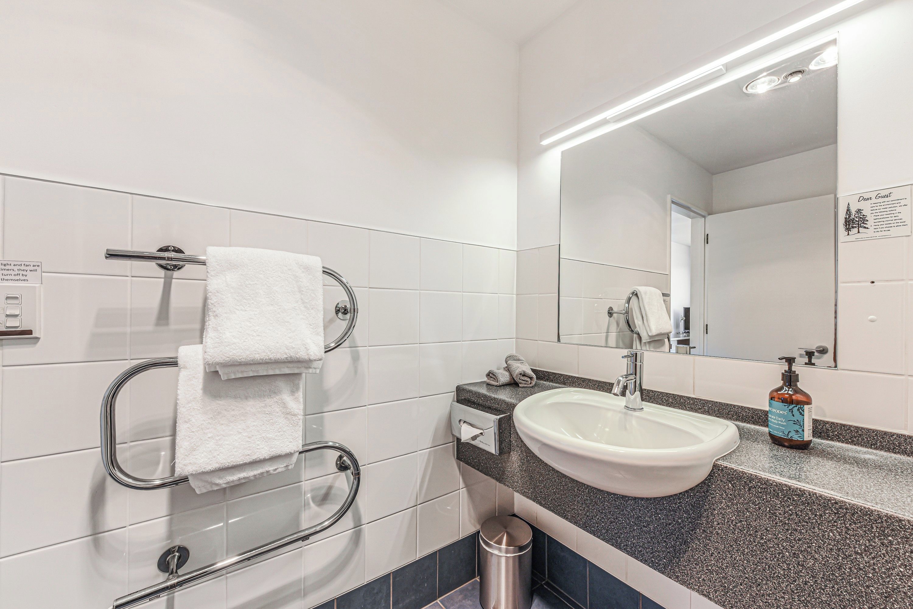 A modern bathroom with a white sink, a mirror, and a hand dryer.