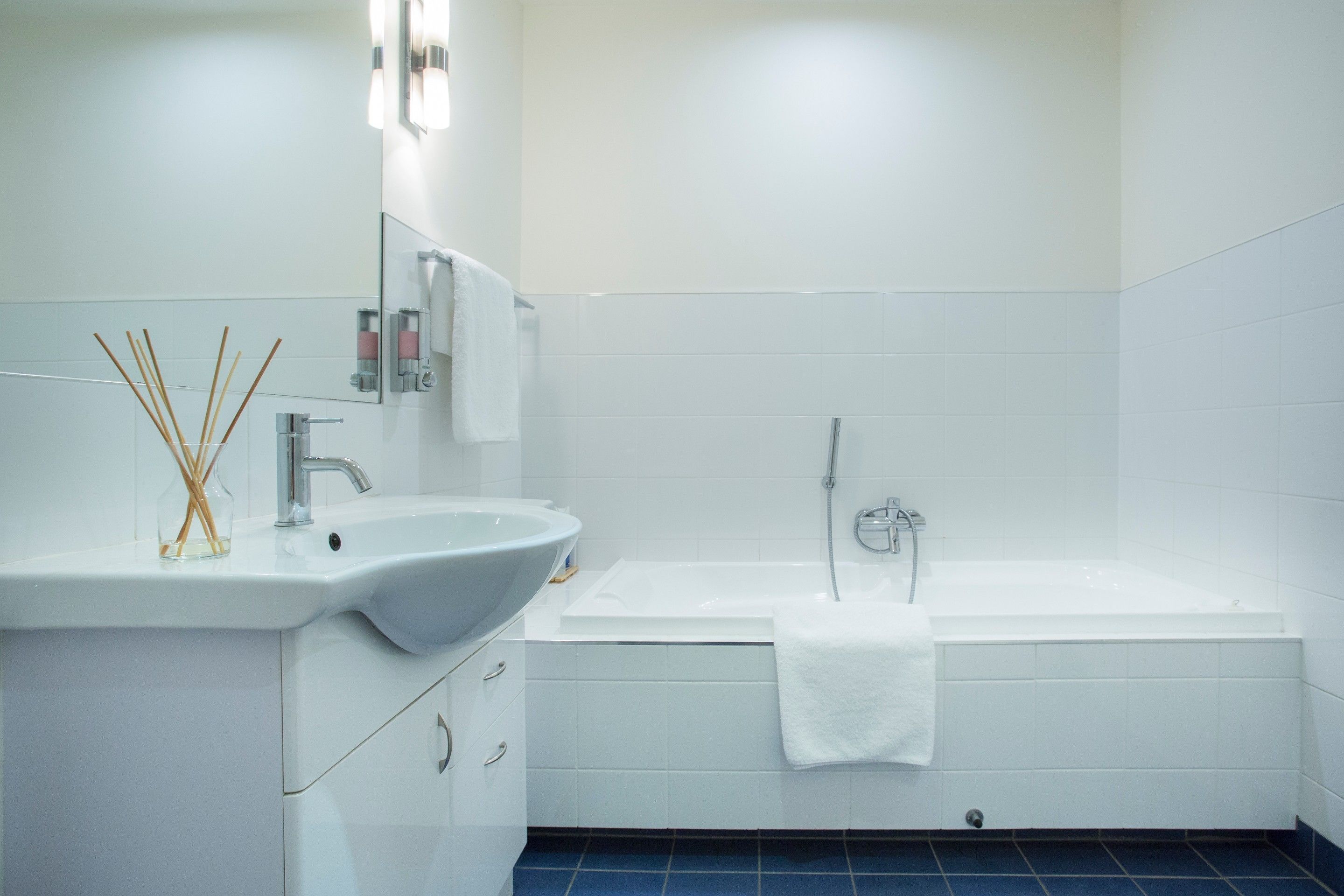 A modern bathroom with a white sink, mirror, and bathtub.