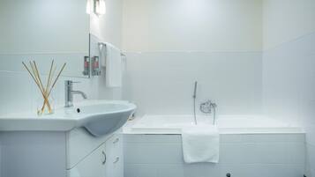 A modern bathroom with a white sink, mirror, and bathtub.