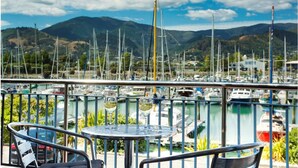 Un balcon avec une table et des chaises donnant sur une marina où sont amarrés de nombreux bateaux.