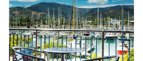 A balcony with a table and chairs overlooking a marina with numerous boats.