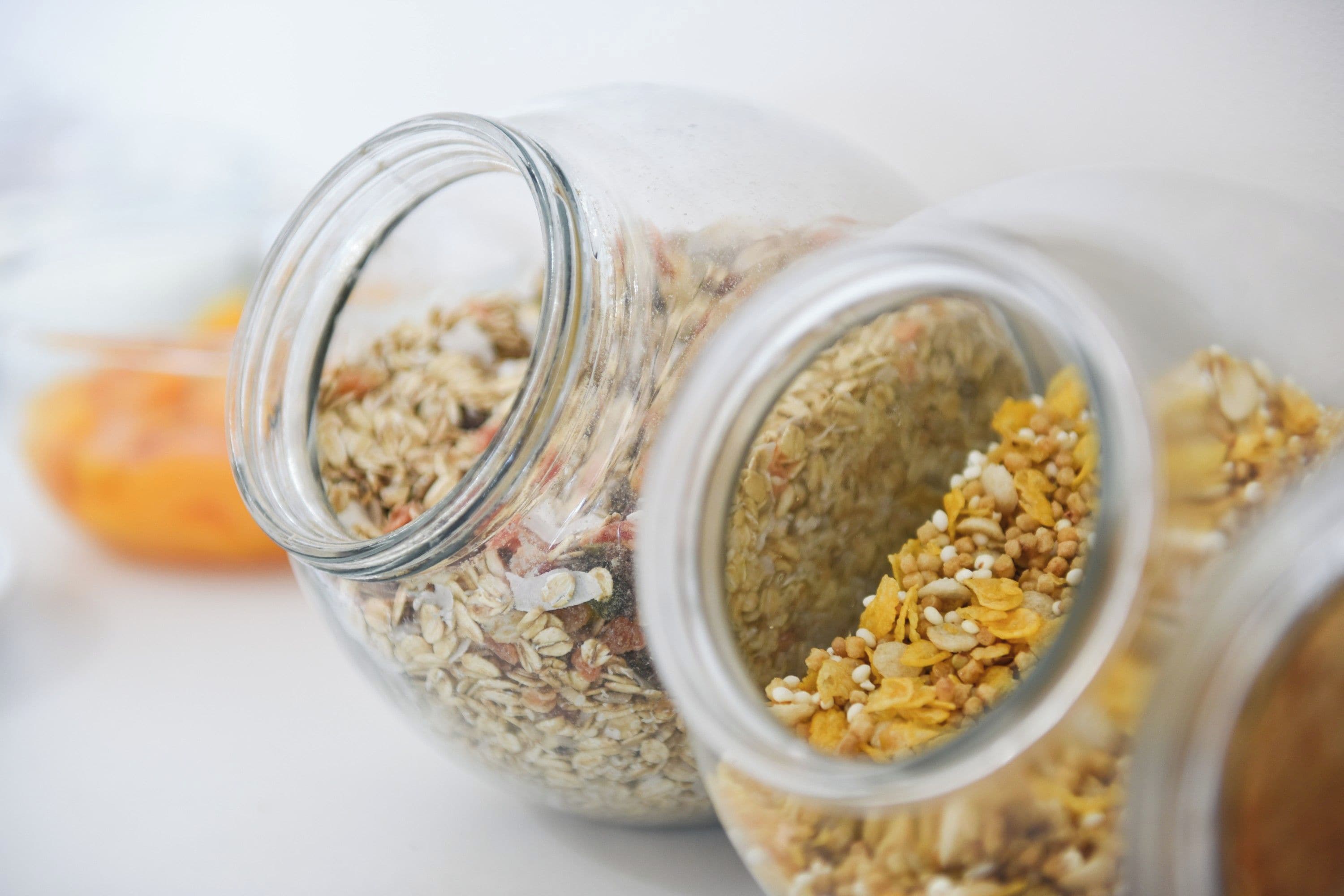 A glass jar with a variety of grains and seeds spilling out.