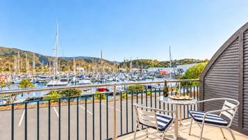 A balcony with two chairs and a table, overlooking a marina with numerous boats.