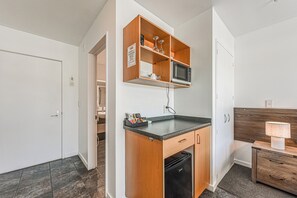 Una cocina compacta con microondas integrado, una pequeña encimera y lavavajillas.