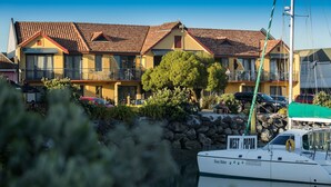 Un hôtel situé au bord de l’eau, avec un toit recouvert de tuiles rouges, des balcons et un bateau amarré à proximité.