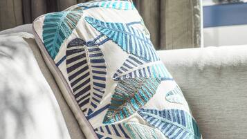 Un cojín con estampado de hojas sobre un sofá.