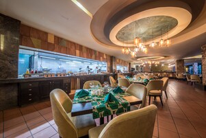 A restaurant with a buffet setup, multiple dining tables, and a modern interior design.