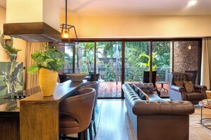 A modern living room with a large window, a dining area, and a seating area with a sofa and chairs.