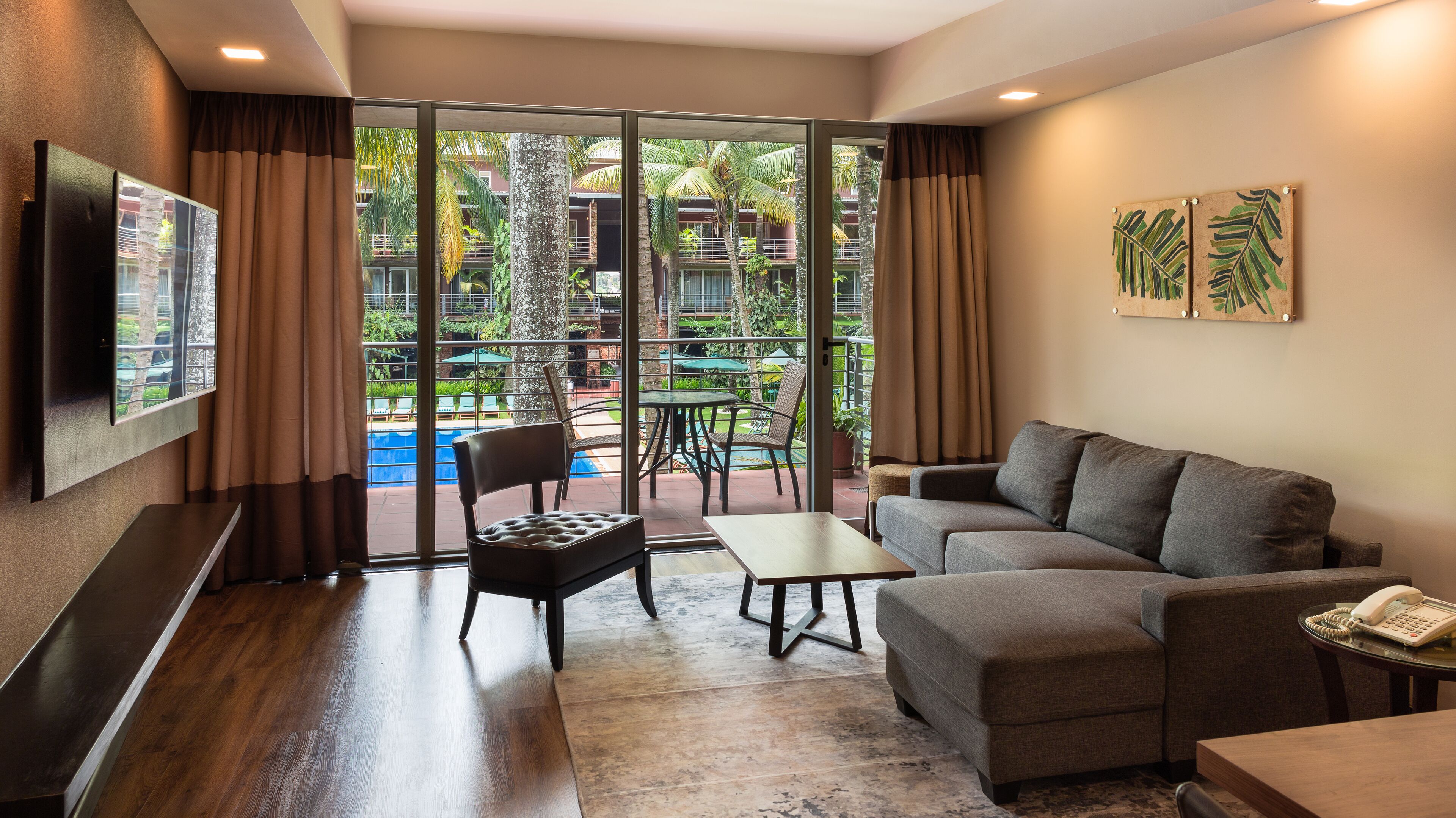Una sala de estar moderna con un sofá, una mesita, una silla y un televisor montado en la pared.