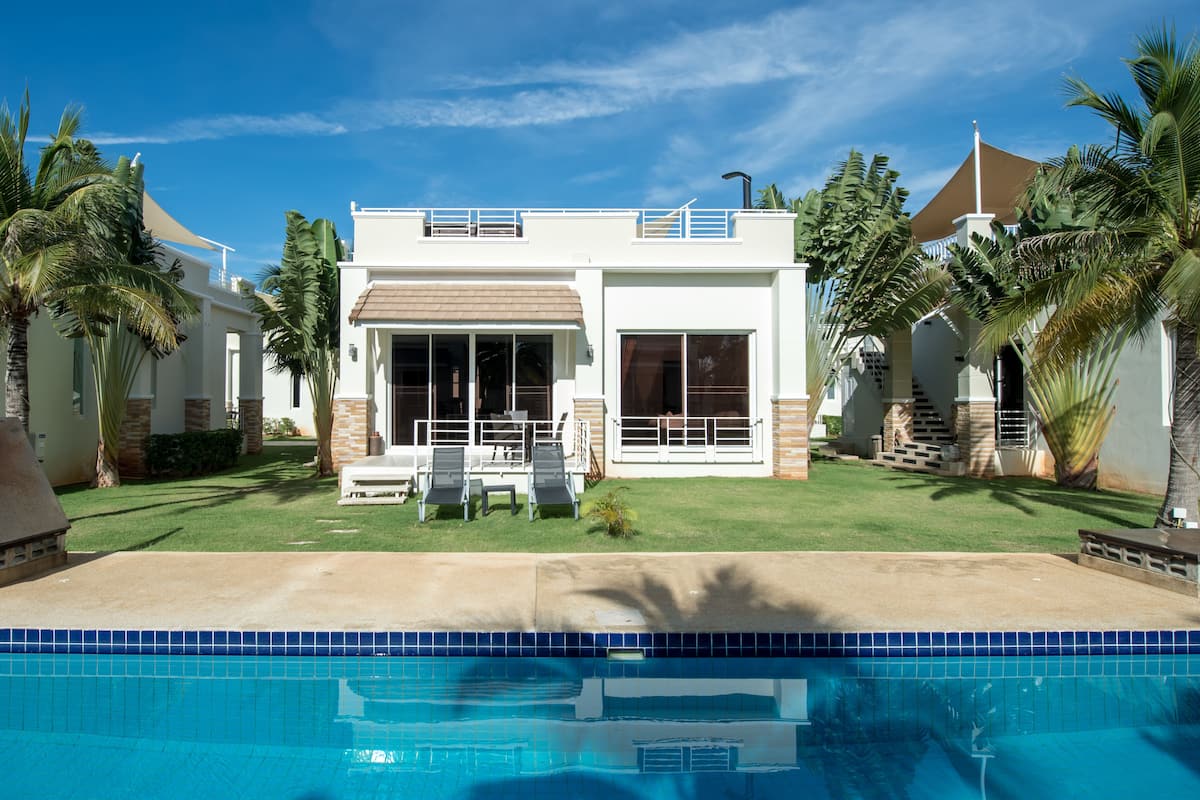 A modern two-story house with a swimming pool in front.