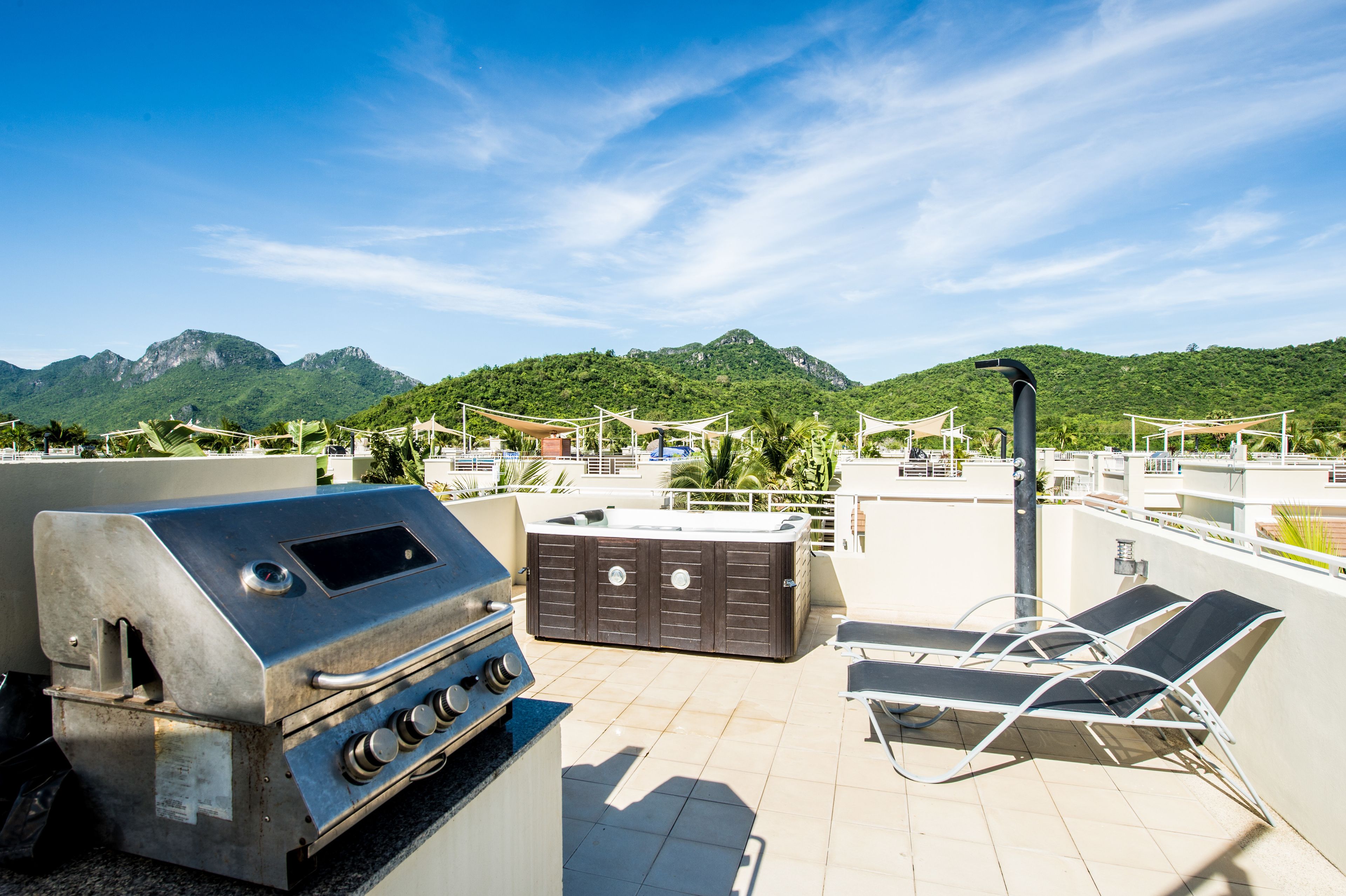 Terraza en la azotea con parrilla, bañera de hidromasaje y sillones de descanso.