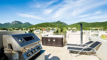 Terraza en la azotea con parrilla, bañera de hidromasaje y sillones de descanso.