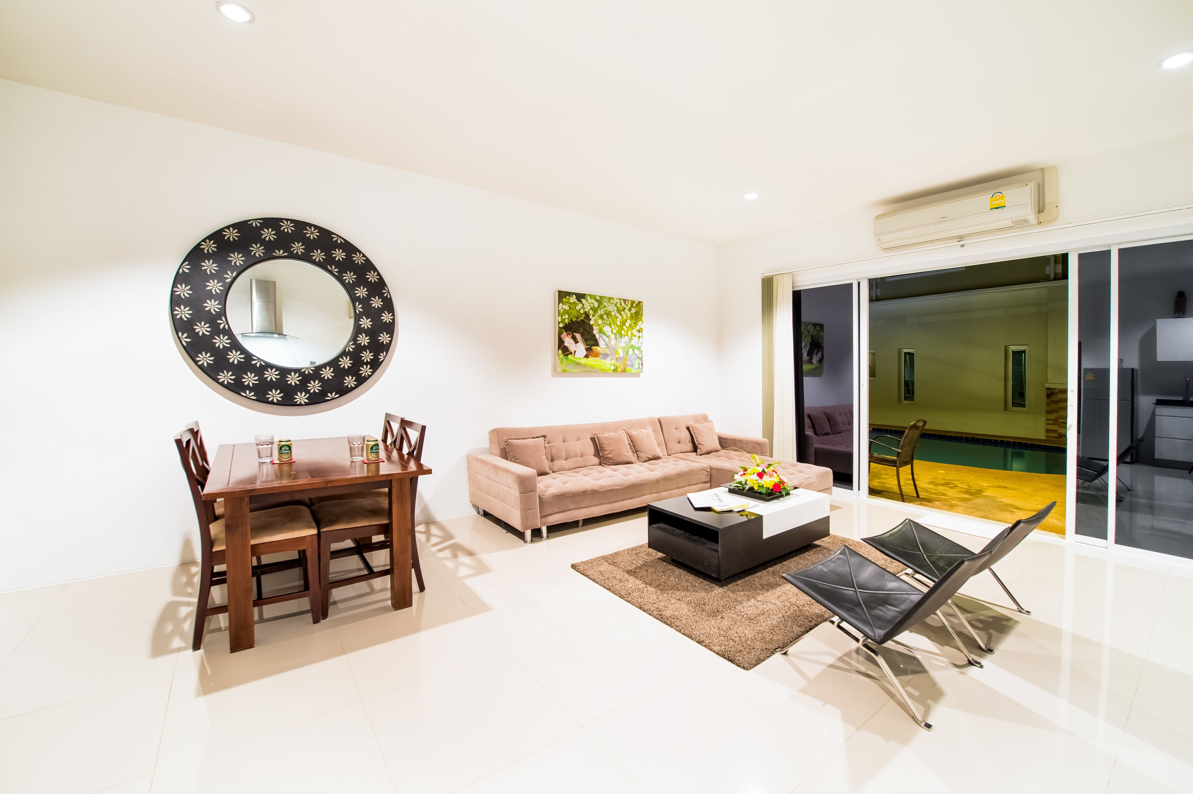 A modern living room with a dining table, sofa, and a large mirror.