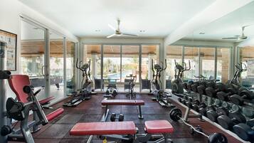 A gym with various exercise equipment, benches, and weight racks.