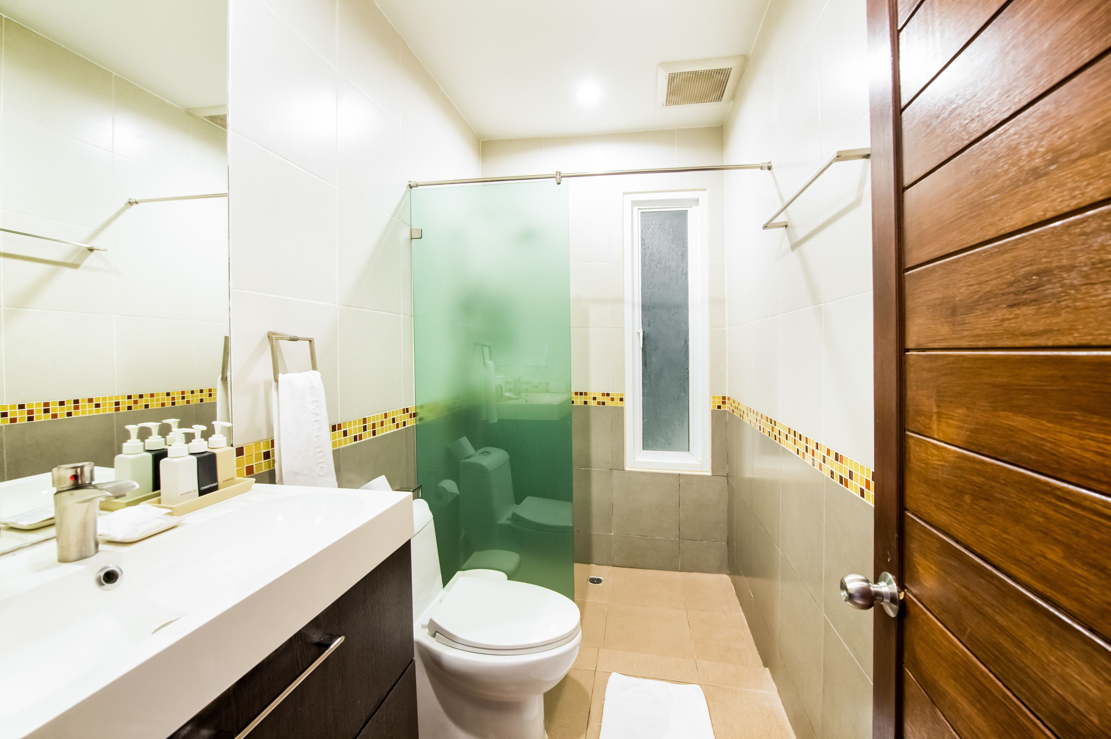Un baño con inodoro, cabina de ducha y lavabo con artículos de aseo.