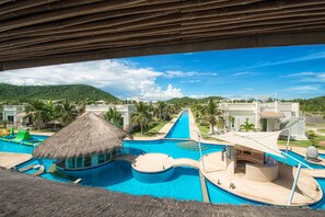A resort with a large swimming pool, a thatched-roof structure, and a view of the mountains. - Oriental Beach Pearl Resort (Sam Roi Yot)