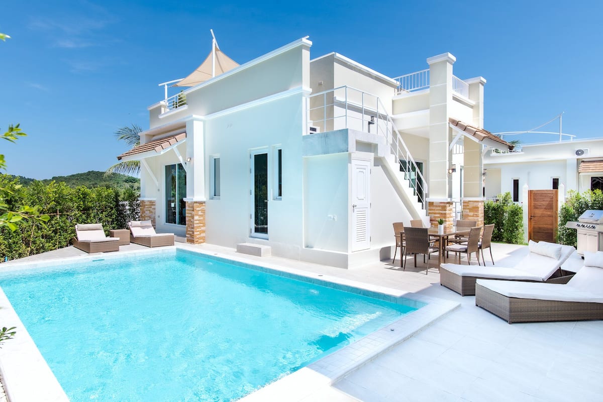 A modern house with a swimming pool, outdoor furniture, and a staircase leading to an upper level.