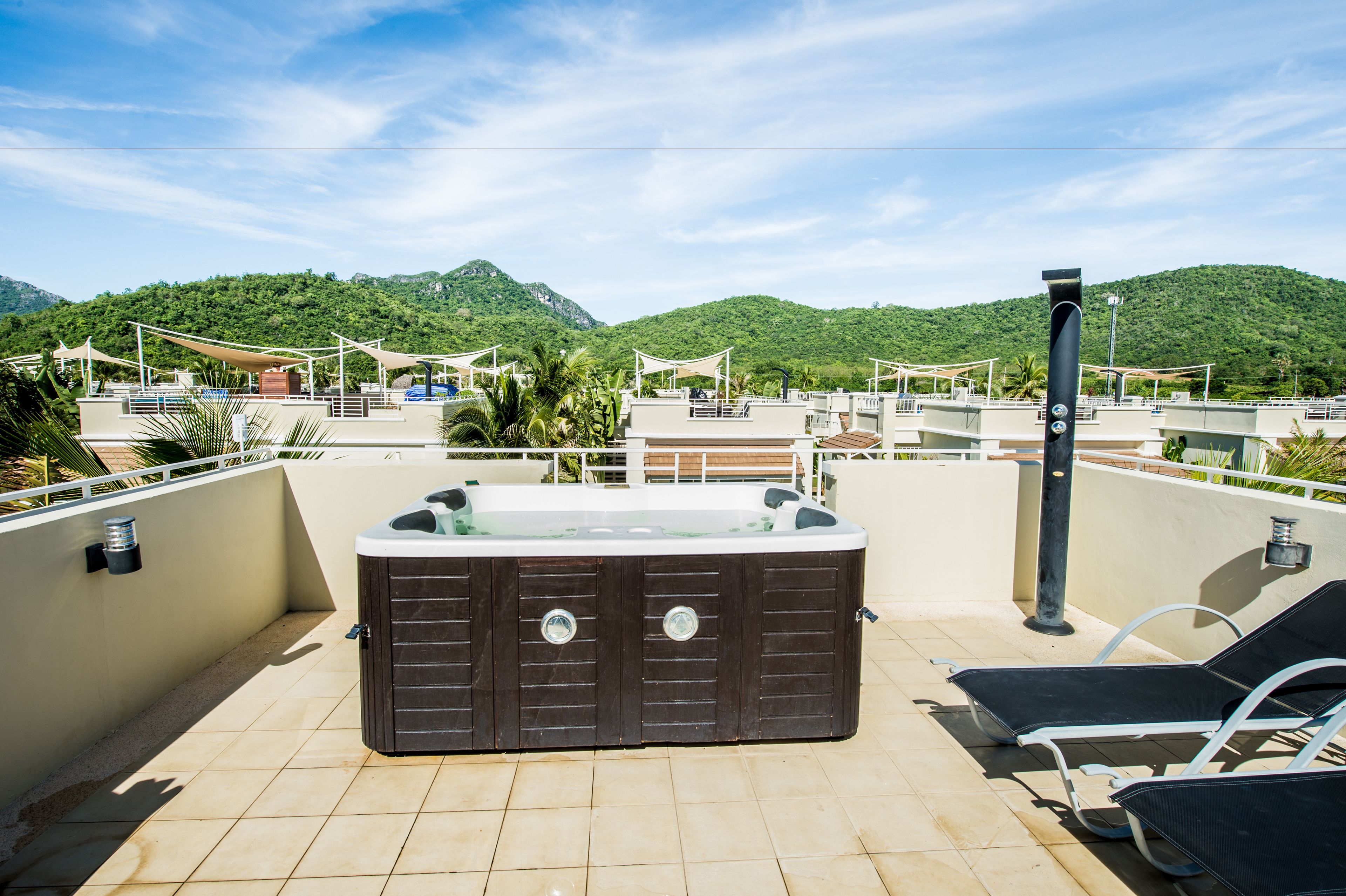 Terraza en la azotea con jacuzzi, sillones de descanso y vistas a colinas verdes.