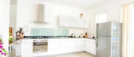 A modern kitchen with white cabinetry, stainless steel appliances, and a built-in oven.