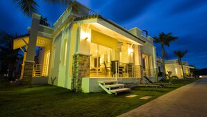A modern house with a balcony, a patio with chairs, and a well-lit entrance. - Oriental Beach Pearl Resort (Sam Roi Yot)
