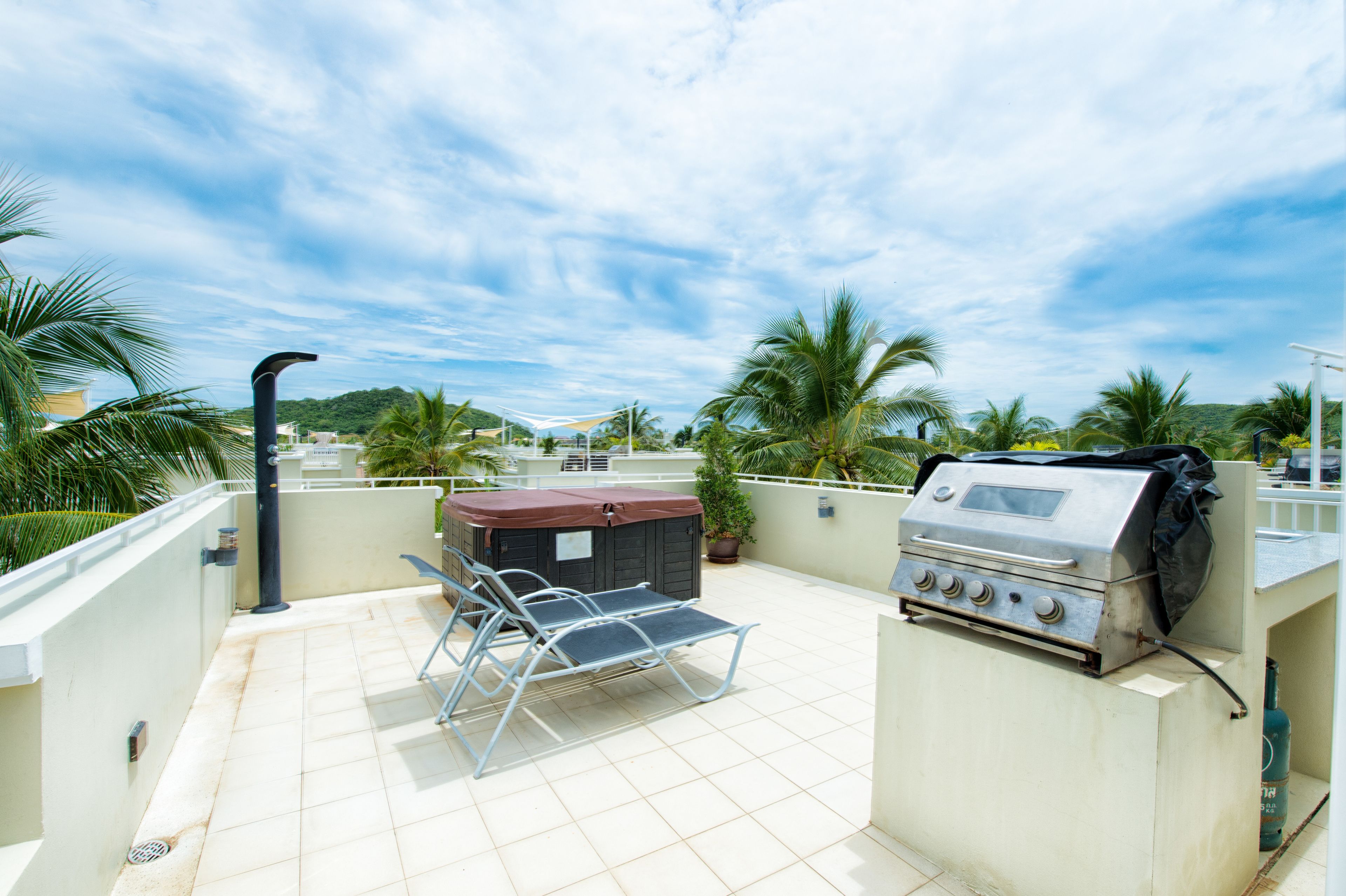 Une terrasse sur le toit équipée d’un barbecue, d’un espace salon couvert et offrant une vue sur le paysage environnant.