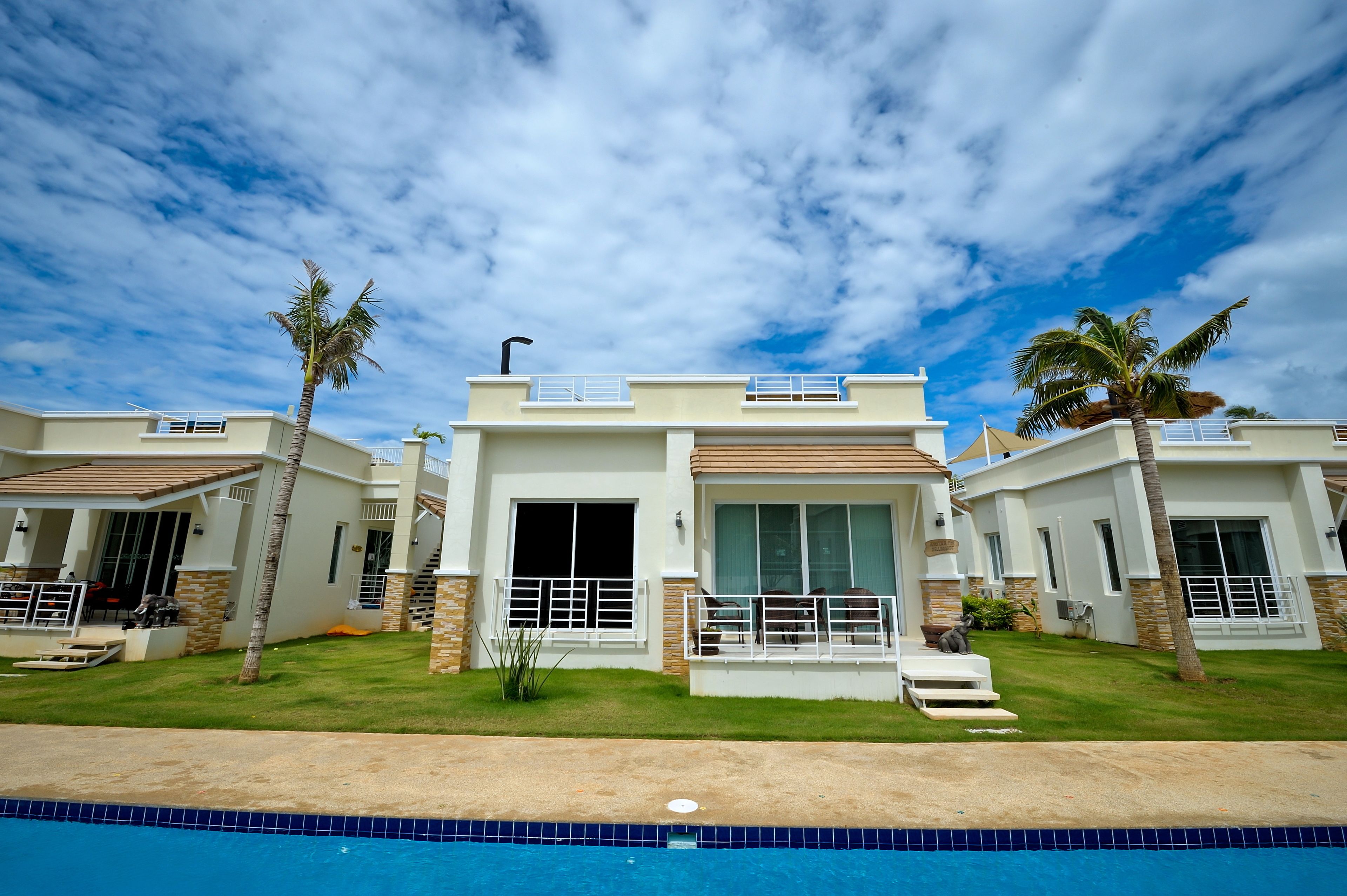 Un moderno resort con edificios de dos pisos, una piscina y palmeras.