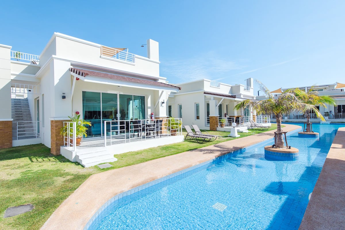 A modern resort with a swimming pool, lounge chairs, and a well-maintained lawn.