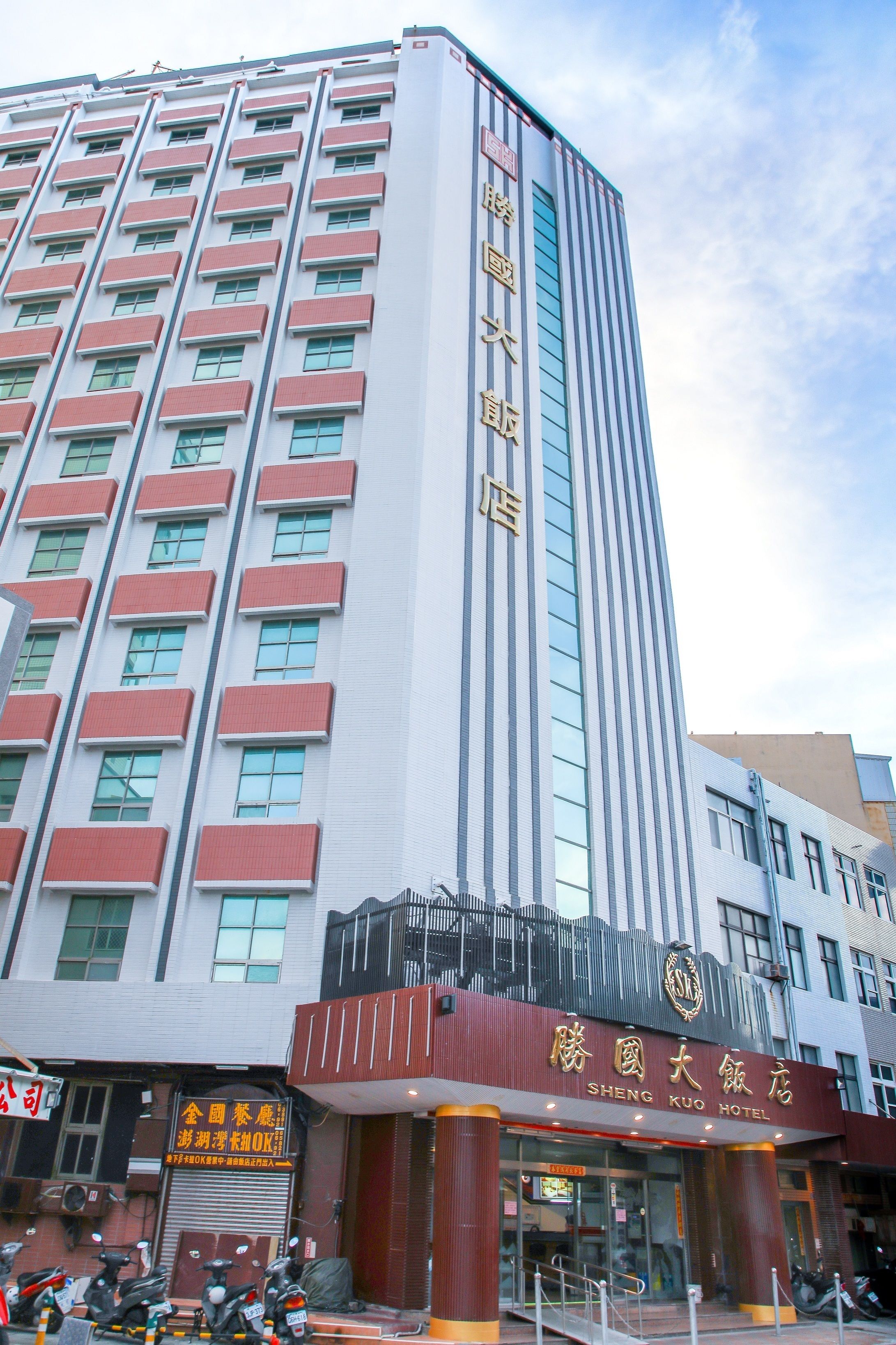 Un edificio de hotel alto con varios pisos y un letrero llamativo del Hotel Shengtai.