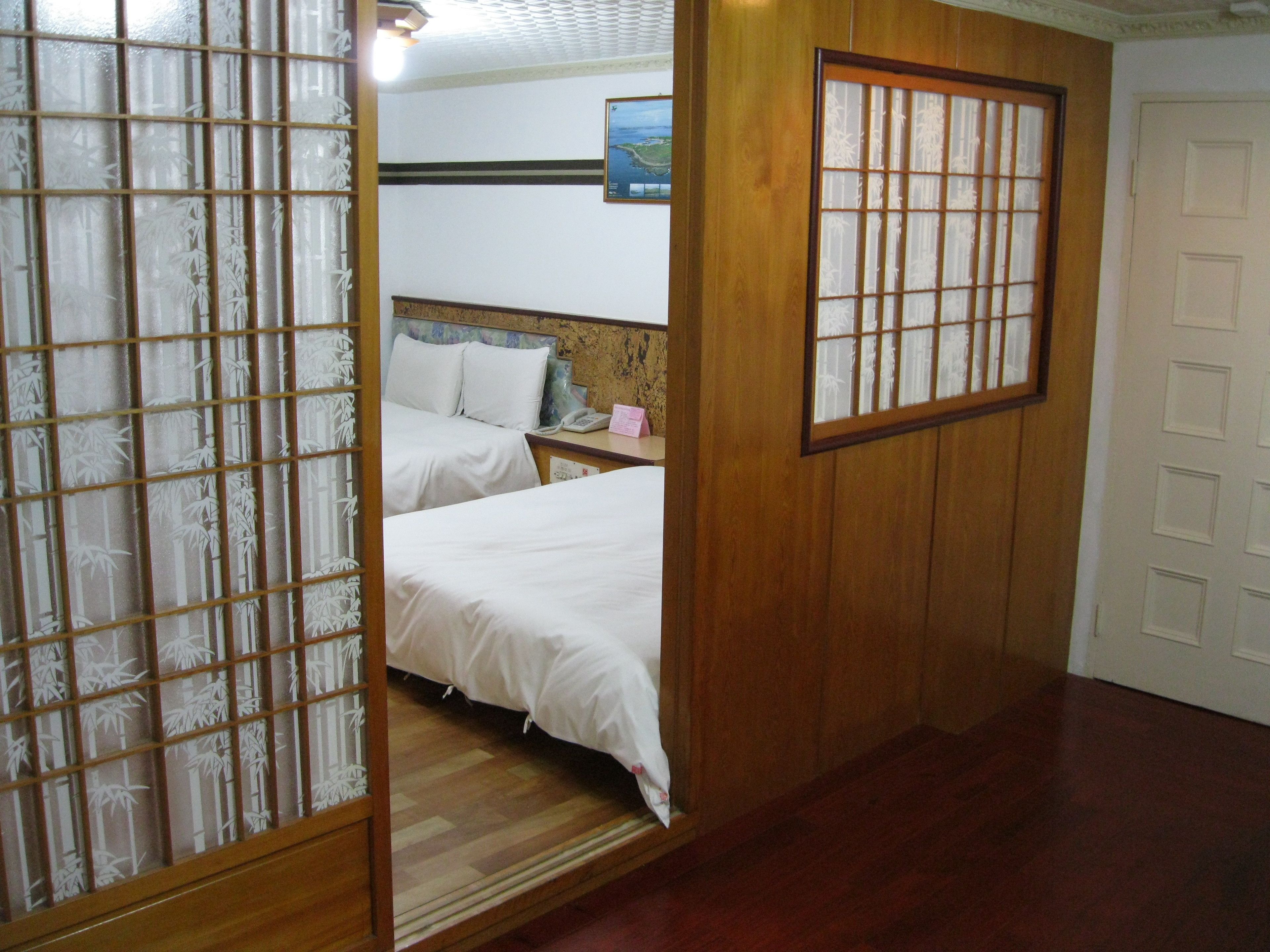 Een traditionele Japanse kamer met twee bedden, een houten schuifdeur en uitzicht op een landschap.'