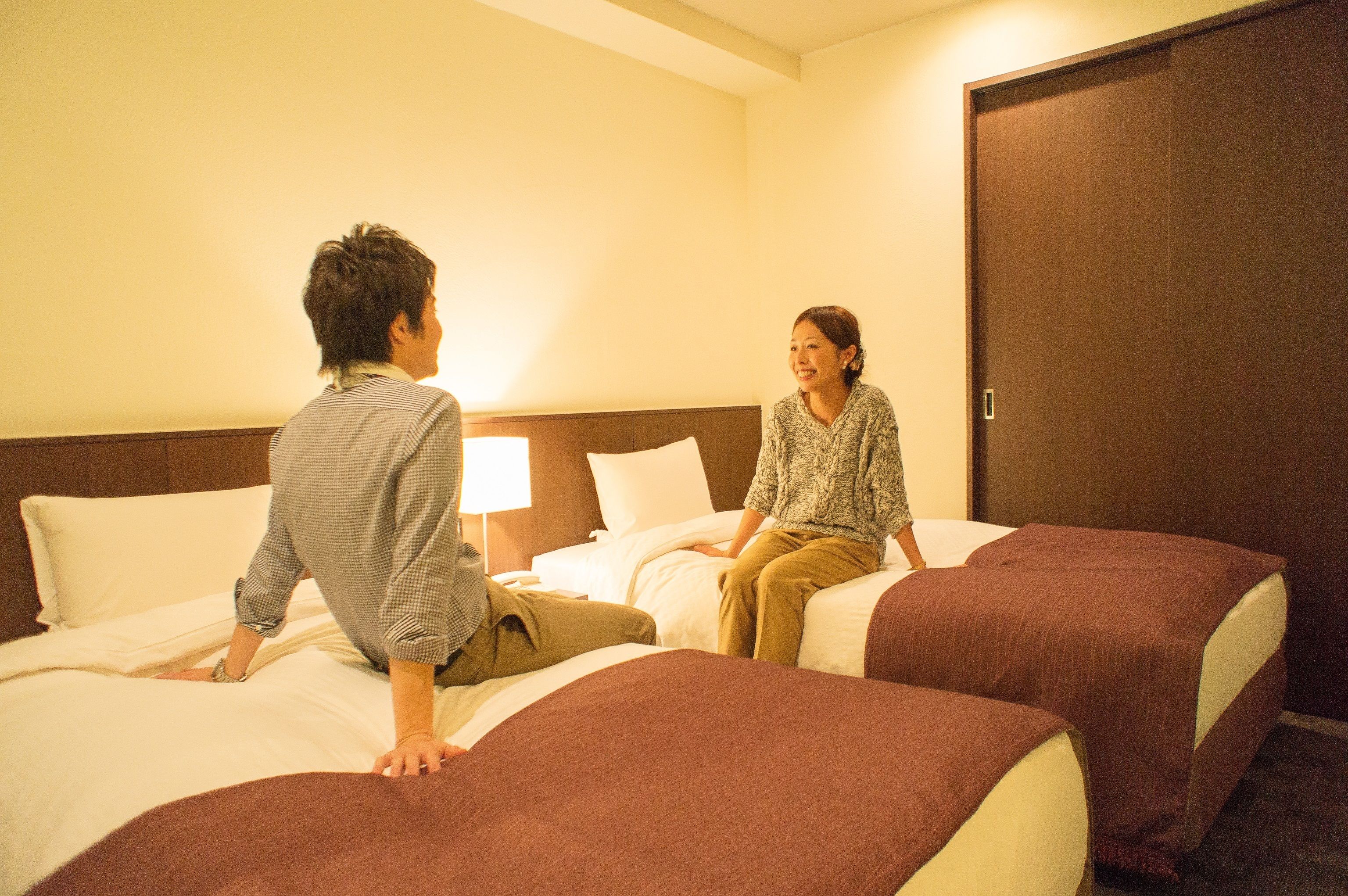 A hotel room with two beds, a wooden headboard, and a door.