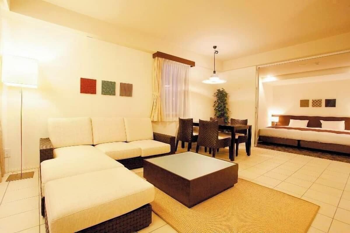Ein Hotelzimmer mit einer Couch, einem Couchtisch, einem Esstisch mit Stühlen und einem Bett.
