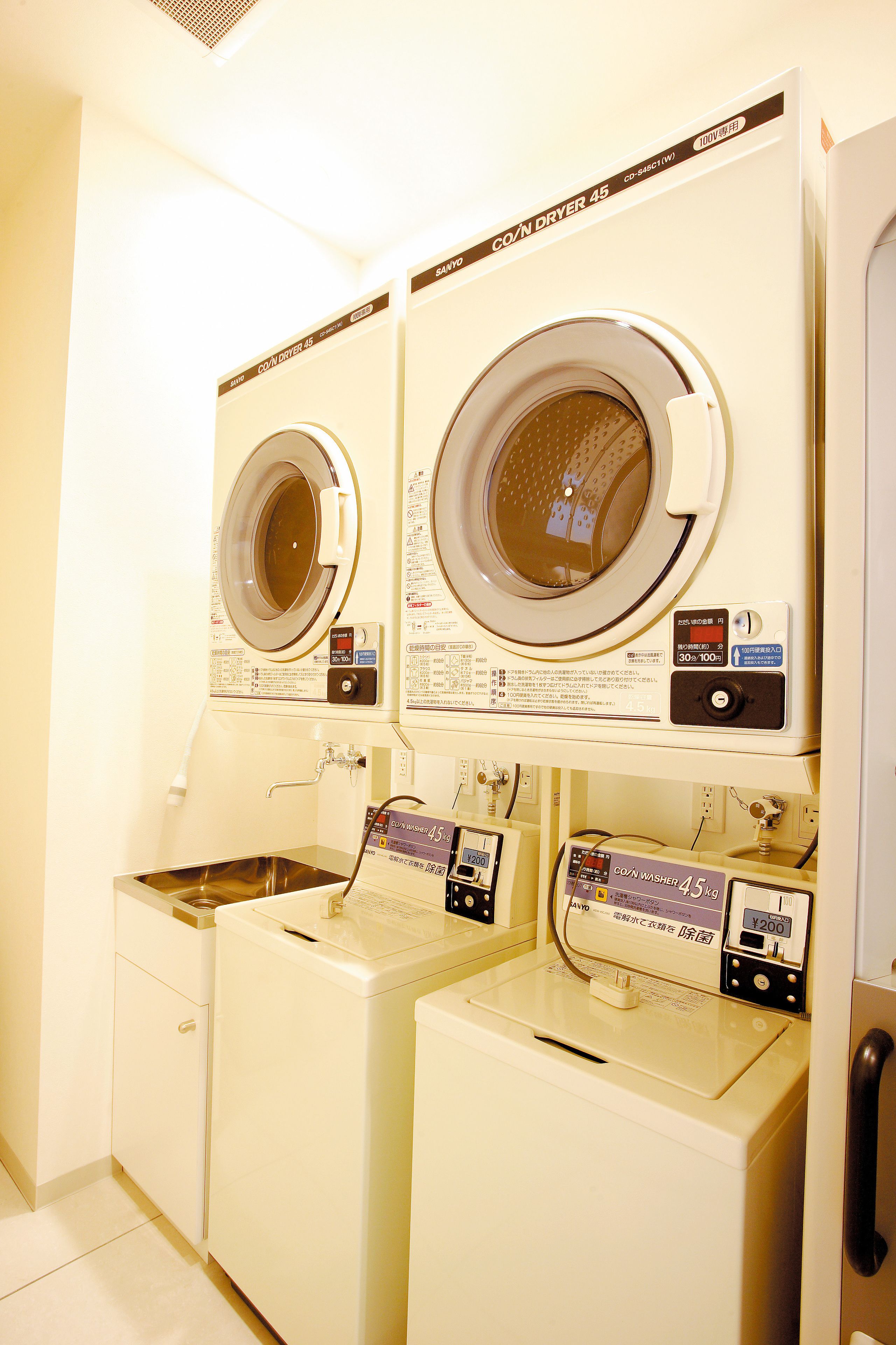 A laundry area with two front-loading washing machines and a sink.
