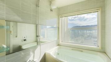 A modern bathroom with a bathtub, a shower, and a window offering a city view.