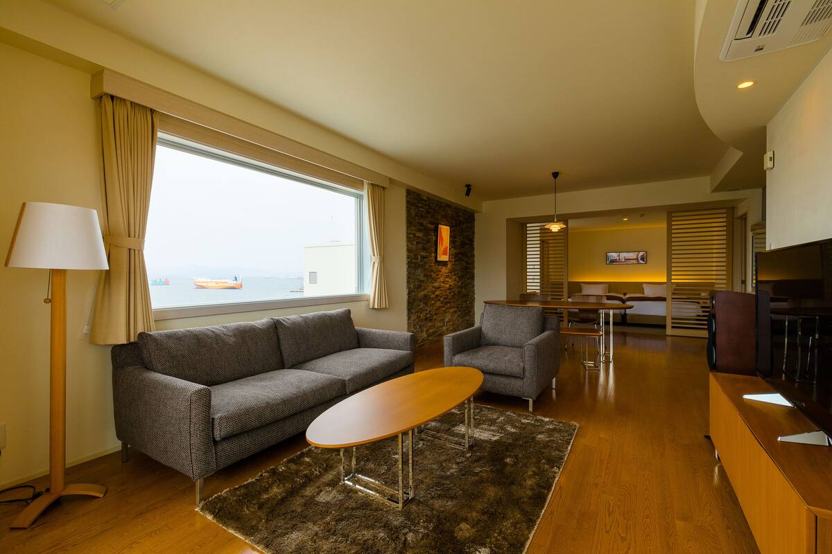 Ein modernes Wohnzimmer mit einer Couch, einem Sessel, einem Couchtisch und einem Fernseher.