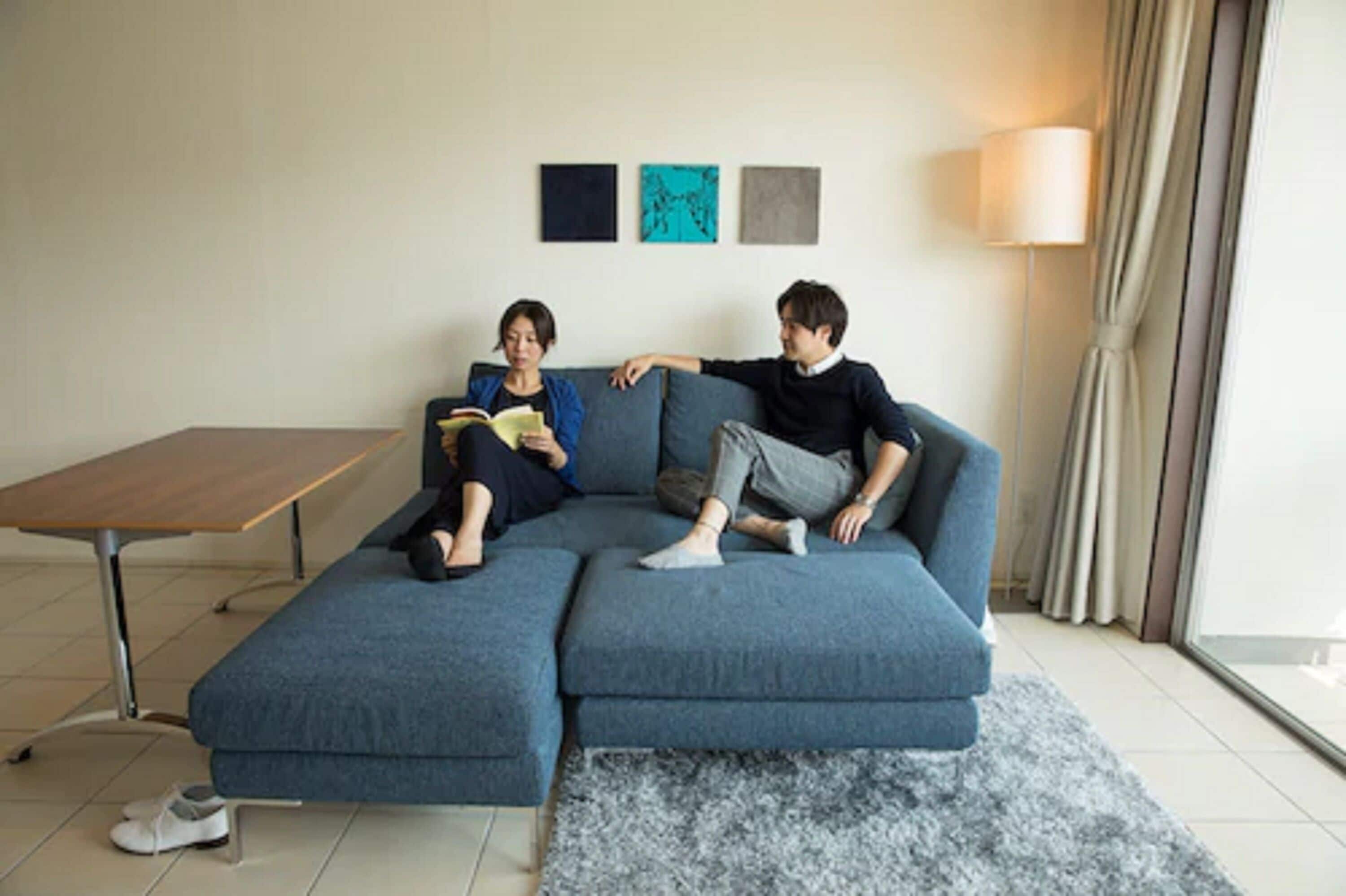 Ein modernes Wohnzimmer mit einem blauen Ecksofa, einem Holztisch und einer Stehlampe.