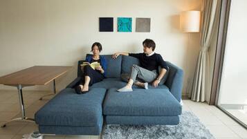 Ein modernes Wohnzimmer mit einem blauen Ecksofa, einem Holztisch und einer Stehlampe.