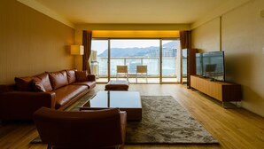 Habitación de hotel moderna con sofá de cuero, televisión de pantalla plana, una mesita de madera y un ventanal con vistas a la ciudad.