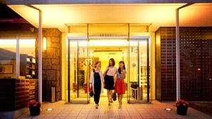 Entrada de un hotel con fachada de vidrio y un letrero que dice "HOTEL & RESORTS".