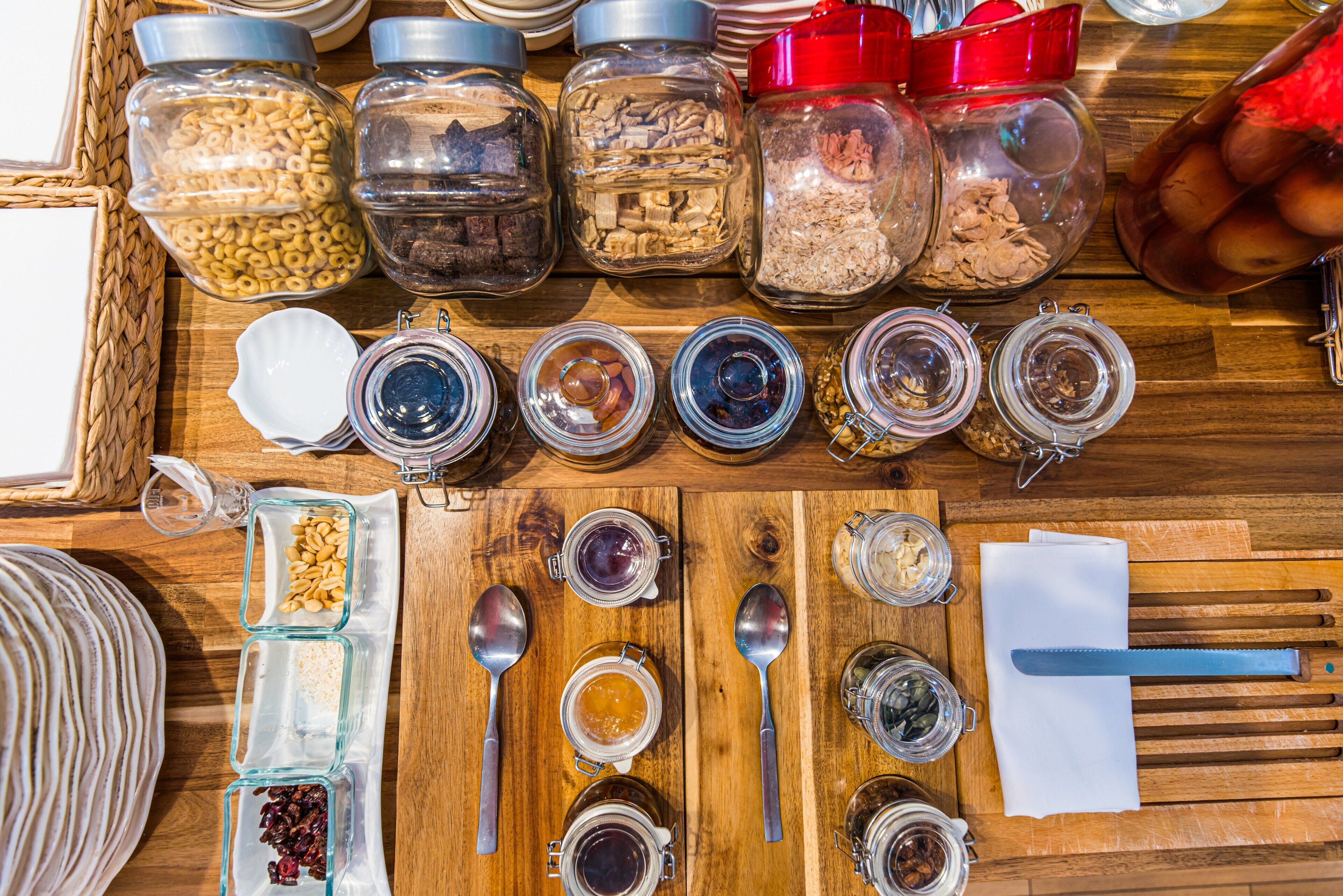A wooden table with various jars containing different food items and utensils.