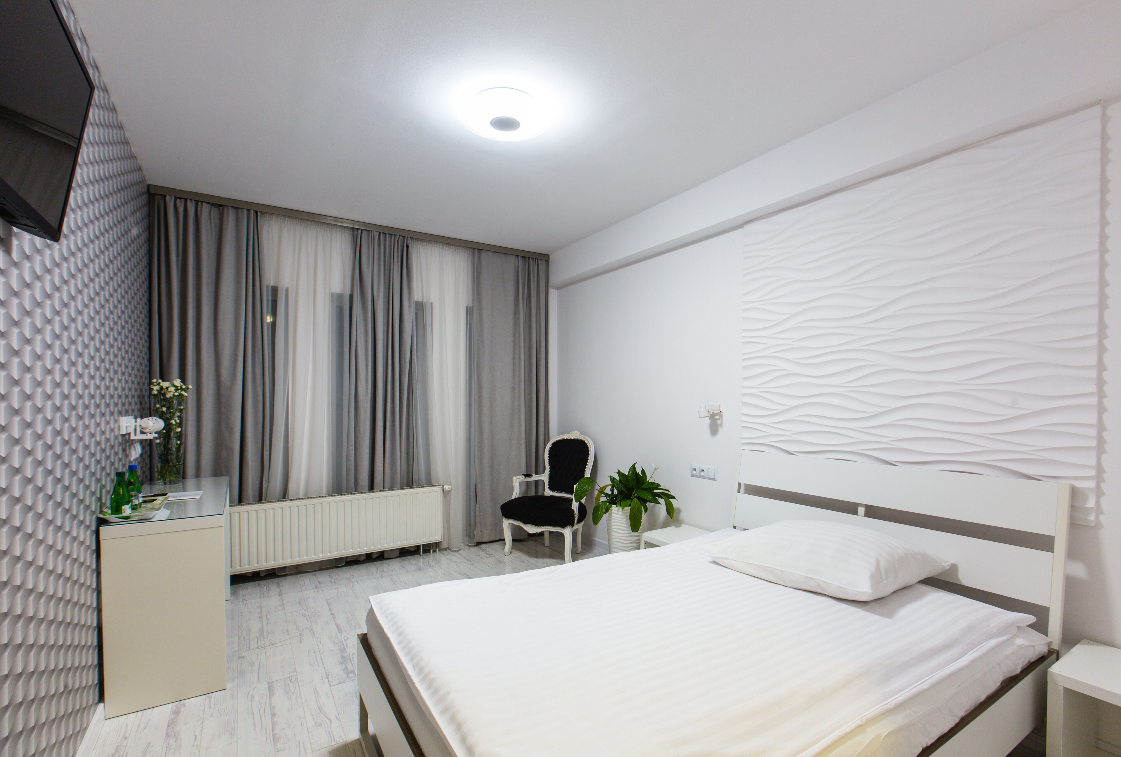 Een moderne hotelkamer met een bed, een bureau, een stoel en een radiator.