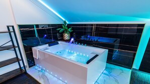 Un baño moderno con una bañera grande, una planta en maceta y una cabina de ducha de vidrio.
