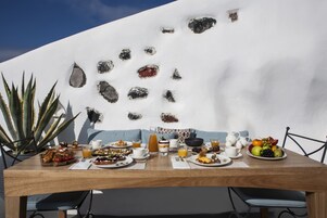 Una mesa de comedor con comida para el desayuno, un sofá azul y una planta de cactus.