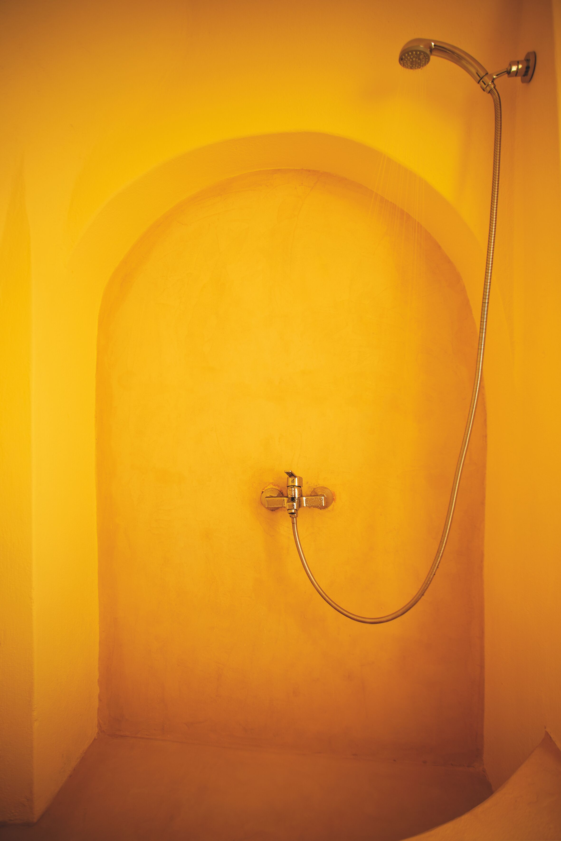 Un baño con ducha, grifo de pared y cabezal de ducha.