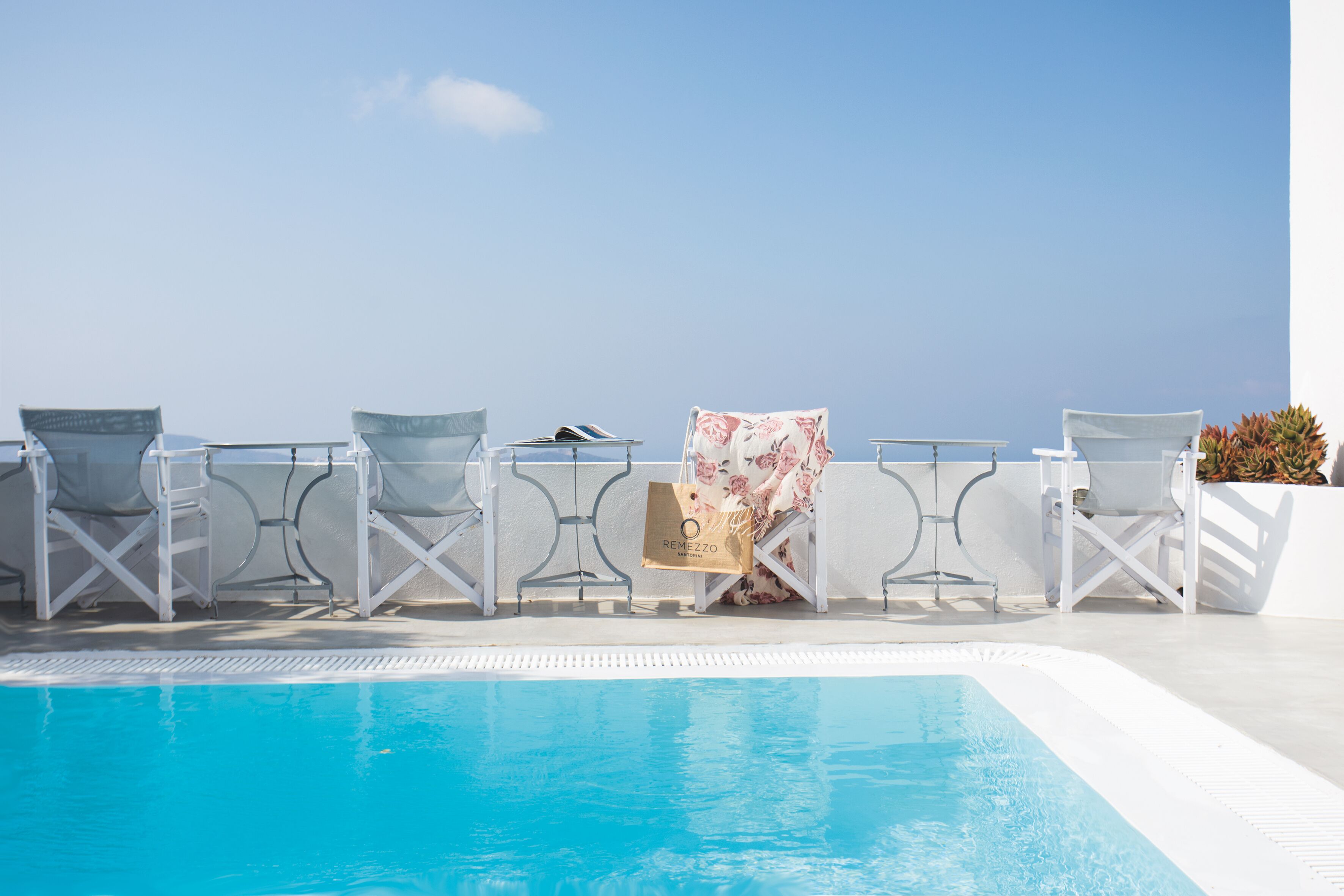 Zona de piscina con sillones de descanso y una vista despejada del cielo.