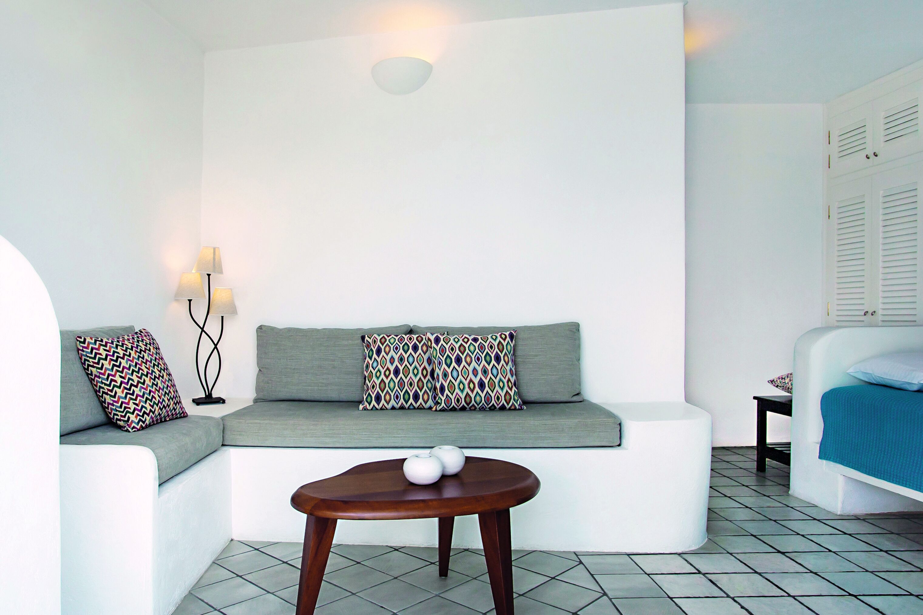 A modern, minimalist room with a sofa, a small round table, and a bed.