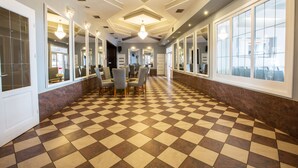 A hotel lobby with a checkered floor, mirrored walls, and a chandelier.